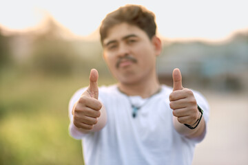 a man standing with his thumbs up. The man acted like someone was giving a compliment to something. set in nature on a sunny afternoon.