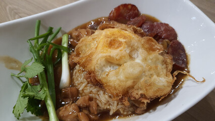 Chicken gravy with rice and top up with chinese sausage and crispy fried egg with spring onion, coriander. Easy, delicious and nutritional value dish for breakfast, lunch or dinner time.