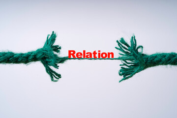 Green rope is breaking with red relation word for broken relationship concept.