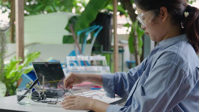 Asian woman programming microcontroller to control Analog Dissolved Oxygen Sensor to find the appropriate value of oxygen in water for use in agriculture in aquaculture. IoT Internet of Thing.