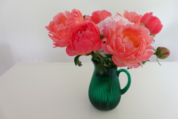Bouquet of pink peonies with green vase on white