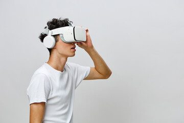 Virtual reality experience, young man wearing VR headset with headphones, grey background, technology concept, immersive gaming, modern lifestyle for innovative media