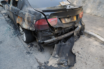 Terrorist incident. Burnt out car with melted parts on a city street showcasing severe fire damage and structural deterioration from a recent terrorism in Israel. A car severely charred and damaged