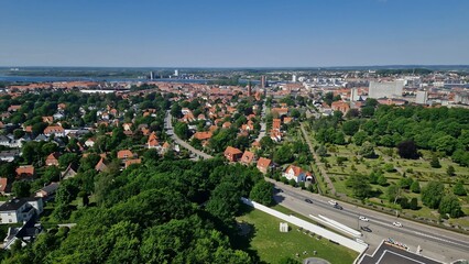 View of a cityscape featuring residential areas with red-roofed houses, green parks