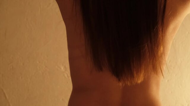 Back of sexy naked girl with long hair. Young confident woman dancing erotic dance. Concept of love and foreplay of sex. Beautiful fit body. Arousal and lust. Unrecognizable person. Body part. 4K