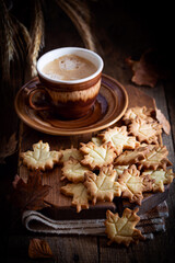 Autumn leaf shaped cookies with coffee cup on wooden board, selective focus