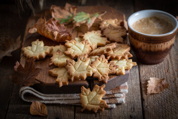 Autumn leaf shaped cookies with coffee cup on wooden board, selective focus