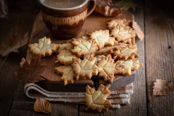 Autumn leaf shaped cookies with coffee cup on wooden board, selective focus