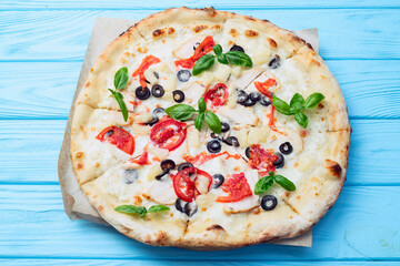 Pizza with mozzarella cheese , olives , chicken , pineapple , basil and tomatoes