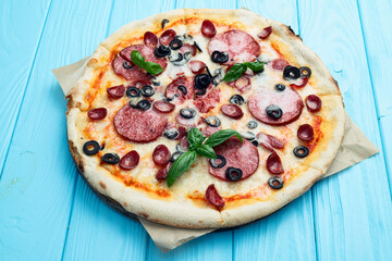 Pizza with mozzarella cheese , salami sausages , olives , and basil