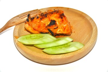 A piece of chicken meat and cucumber slices on a bowl on a white background