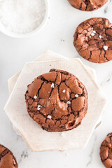 Fudgy brownie cookies with flaky salt on a white background