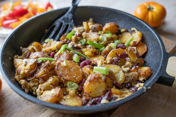 Homemade vegetarian fried potatoes with eggs, onions and kidney beans in a frying pan
