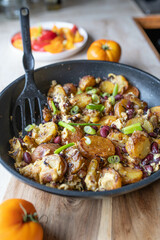 Homemade vegetarian fried potatoes with eggs, onions and kidney beans in a frying pan