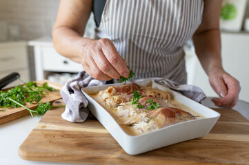 Woman garnishing oder finishing a homemade cooked dinner with chopped parsley. Delicous oven braised tukry roulades