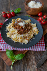 Plate with original ragu alla bolognese. Served with tagliatelle and grated parmesan cheese on rustic and wooden table background