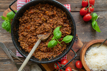 Original Ragú alla Bolognese in a casserole on rustic and wooden table background. Italian cuisine