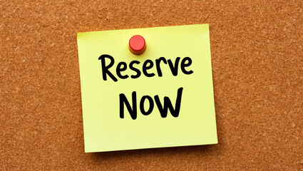 Reserve now word written on a note sticky on corkboard