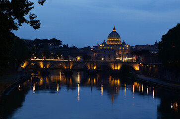 Obraz premium Castel Sant'Angelo in Rome, beautifully illuminated and reflecting on the calm river. The dark blue sky contrasts with the warm lights of the castle.