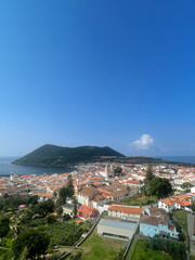 A picturesque view of Angra do Heroísmo in the Azores, featuring historic buildings, red rooftops, and lush greenery under a clear sky. Ideal for themes of travel, heritage, and island landscapes. © Andre Sousa