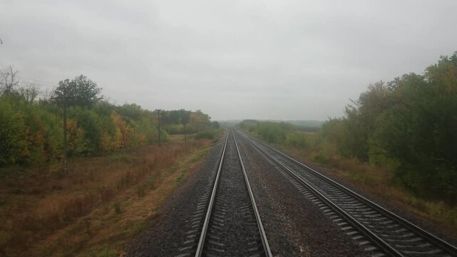Video footage from the last carriage of a moving train. Railway. Autumn landscape. Cloudy day.