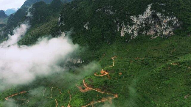Drone of mountains, nature and highway for travel, adventure and holiday with eco tourism background. Scenery or aerial view of green landscape, clouds and river with road in Vietnam, Ma Pi Leng Pass