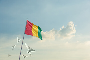 Guinea flag waving with flying doves in beautiful sky. Guinea flag for Republic Day and Independence Day.