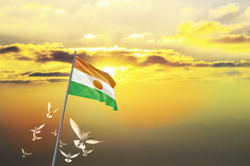 Niger flag waving with flying doves against sunset or sunrise. Niger flag for Republic Day and Independence Day.