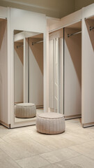Empty fitting room with mirrors and a beige ottoman on a tiled floor. Minimalist design with neutral tones. Concept of modern interior design.