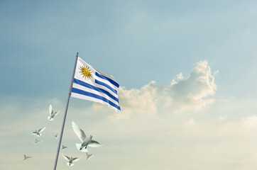 Uruguay flag waving with flying doves in beautiful sky. Uruguay flag for Republic Day and Independence Day.