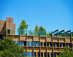 Contemporary building with rooftop garden. Green space in urban architecture under clear blue sky.