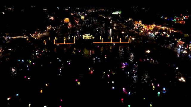 Stunning drone footage captures the tranquil beauty of Hoi An's Old Town historic Unesco heritage site at night, as colorful lantern boats drift along the Thu B&ocirc;n River.