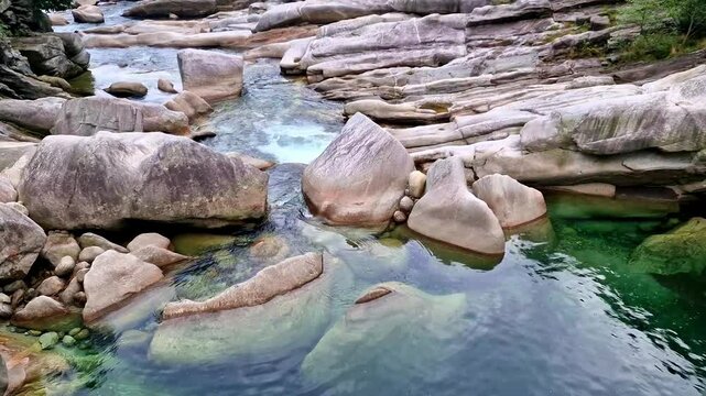 POV View from Giant Granite Boulders over Emerald Verzasca River in Ticino Switzerland. Handheld Cinematic Camera Moving past Rocks and Waterfalls. Traditional Alpine Nature Trail. 4K