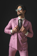 sexy fashion businessman with sunglasses looking to side and fixing suit