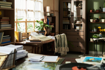 Cozy home office with sunlight illuminating books and desk, adorned with a green chair and various...