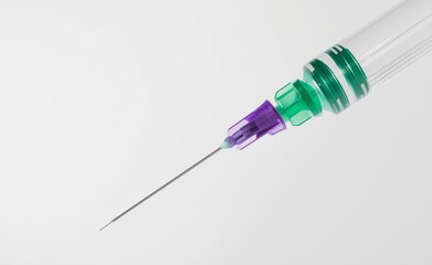 A medical syringe with a green and purple cap on a plain white background.