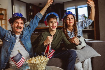 Fototapeta premium Latino family is watching football match with American flags
