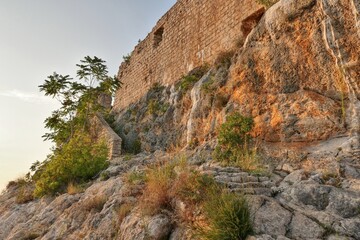 Southwestern part of ruins of medieval castle Fortica, Novigrad town, Zadar district, Croatia, with visible calcificate deposit after flowing mineralised water on rock in the past. Evening sunshine.