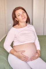 Joyful expectant mother relaxing at home in comfortable maternity wear.