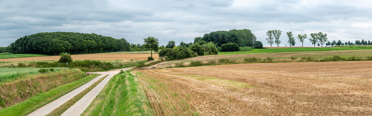Winding road through the harvested fields and hills at the Flemish countryside around Breisem, Belgium