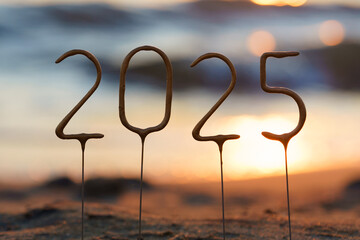 Close-up of the number 2025 against the background of sparkling sea water on a golden beach. The...