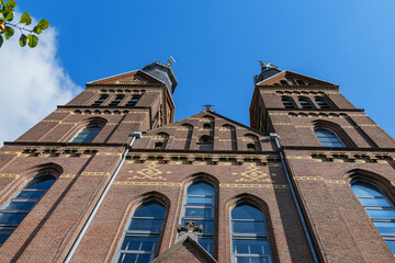 View of Neo-Gothic Post Horn Church (Posthoornkerk, 1863) with three slender towers on bustling Haarlemmerstraat - one of most important surviving XIX century churches. Amsterdam, the Netherlands.