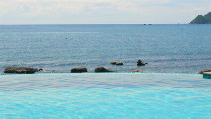 Fototapeta premium Infinity pool overlooking tranquil ocean, showcasing serene coastal beauty and vacation relaxation.