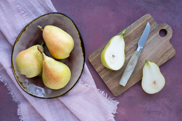 A plate with whole ripe pears and cut juicy fruit.