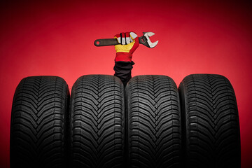 Car tires service and hand with spanner of mechanic or driver  on red background, safety driving on a road with wheels © ValentinValkov