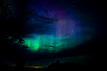 Northern lights dancing over the sky sky in the country road