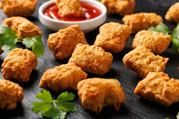 Homemade crispy fried chicken nuggets served on a stone board