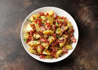 German Potato Salad with bacon and herbs in a white plate