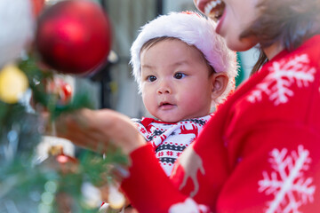 Baby in red hat on Christmas Day, filled with camera, presents and Christmas tree.