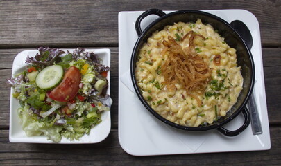 Nudeln Spaetzle with cheese, roasted onion and vegetable salad 
